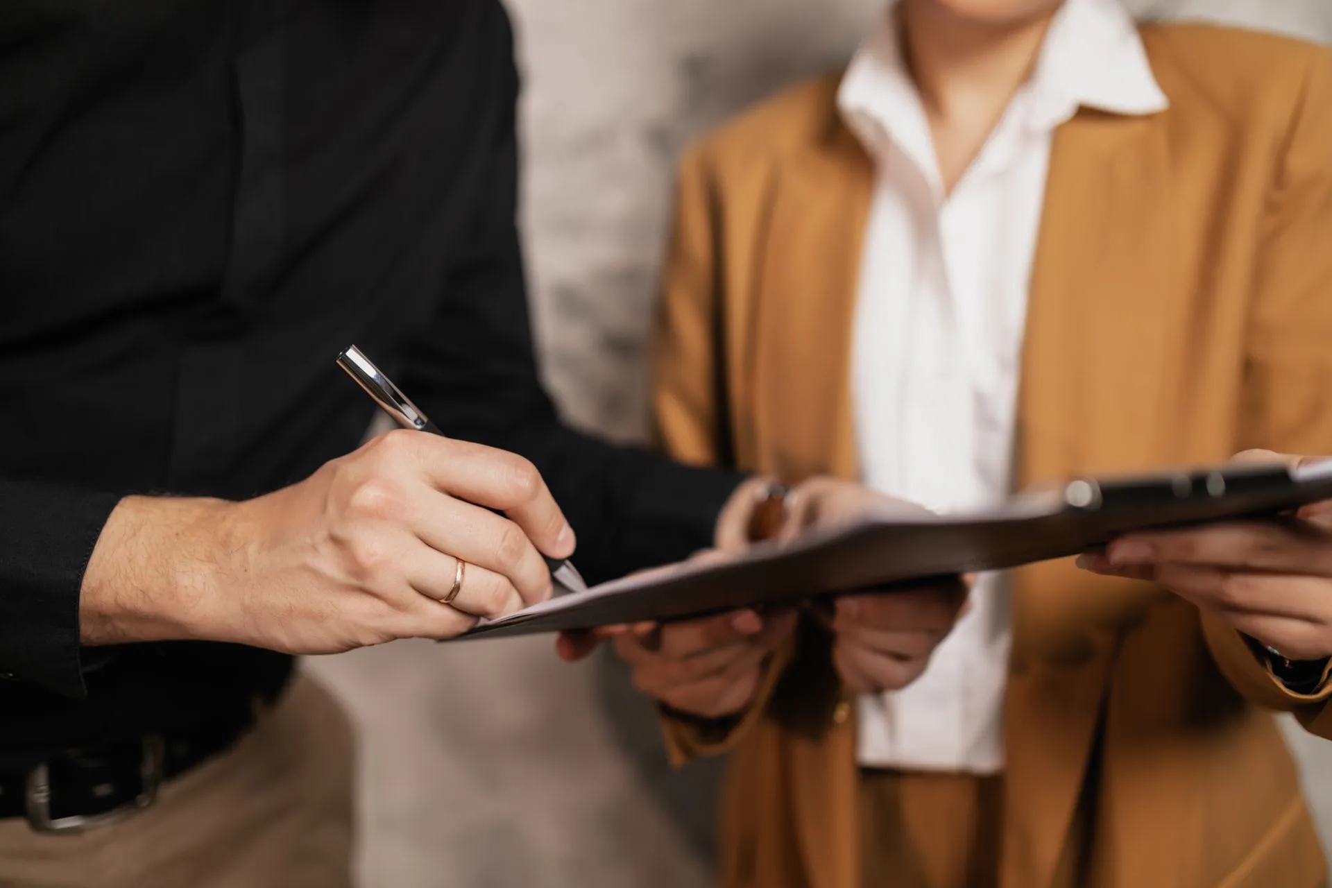 Two people signing documents at an office desk